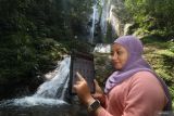 Nasabah CIMB Niaga melakukan transaksi menggunakan aplikasi OCTO Mobile di kawasan wisata alam air terjun Dolo, Kabupaten Kediri, Jawa Timur, Minggu (24/8/2025). Aplikasi perbankan digital dari CIMB Niaga OCTO Mobile memungkinkan masyarakat melakukan berbagai transaksi keuangan seperti cek saldo, transfer antar bank, bayar tagihan top-up e-wallet, pembukaan rekening dan investasi di mana saja dan kapan saja secara mudah sekaligus aman. Antara Jatim/Prasetia Fauzani/um
