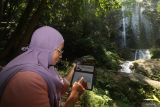 Nasabah CIMB Niaga melakukan transaksi menggunakan aplikasi OCTO Mobile di kawasan wisata alam air terjun Dolo, Kabupaten Kediri, Jawa Timur, Minggu (24/8/2025). Aplikasi perbankan digital dari CIMB Niaga OCTO Mobile memungkinkan masyarakat melakukan berbagai transaksi keuangan seperti cek saldo, transfer antar bank, bayar tagihan top-up e-wallet, pembukaan rekening dan investasi di mana saja dan kapan saja secara mudah sekaligus aman. Antara Jatim/Prasetia Fauzani/um