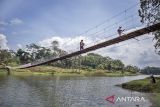 Warga berjalan di atas Jembatan Gantung Sungai Cicadas di Desa Karanganyar, Cililin, Kabupaten Bandung Barat, Jawa Barat, Minggu (31/8/2025). Vertical Rescue Indonesia (VRI) membangun jembatan gantung sepanjang 120 meter yang menghubungkan Desa Karanganyar, Kecamatan Cililin dengan Desa Suka Mulya, Kecamatan Cipongkor guna mempermudah masyarakat yang selama ini kesulitan mengakses layanan pendidikan, ekonomi, kesehatan, hingga administrasi kependudukan akibat kondisi geografis yang terisolasi. ANTARA FOTO/Abdan Syakura/agr