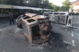 Warga melintas di samping mobil yang terbakar pascakerusuhan di halaman gedung Pemkab Kediri, Jawa Timur, Minggu (31/8/2025). Kerusuhan dan penjarahan oleh massa tidak dikenal pada Sabtu (30/08/2025) malam tersebut mengakibatkan gedung pemkab, gedung DPRD, Samsat, dan puluhan mobil terbakar. ANTARA Jatim/Prasetia Fauzani/mas.