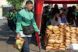 Pengemudi ojek online menerima bantuan beras seusai doa bersama di parkir timur GOR Delta Sidoarjo, Jawa Timur, Jumat (5/9/2025). Pemerintah Kabupaten (Pemkab) Sidoarjo membagikan bantuan beras untuk membantu perekonomian pengemudi ojek online dan mempererat jalinan silaturahmi. Antara Jatim/Umarul Faruq