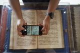 Pengunjung mengamati teks naskah kuno berbahasa jawa dan arab pegon dalam pameran naskah kuno di Tulungagung, Jawa Timur, Selasa (9/9/2025). Pameran ini digelar dengan tujuan mengedukasi publik akan pentingnya pelestarian warisan intelektual Nusantara berbentuk naskah kuno yang ada di balai arsip daerah maupun koleksi pribadi warga. Antara Jatim/Destyan Sujarwoko/um