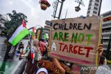 Massa aksi yang tergabung dalam Solidaritas Seni Untuk Palestina membentangkan poster saat mengikuti aksi di depan Monumen Dasasila Bandung di Jalan Asia Afrika, Bandung, Jawa Barat, Jumat (19/9/2025). Dalam aksinya mereka mengajak masyarakat untuk menyalakan alarm secara bersama-sam sebagai bentuk protes terhadap tindakan Israel yang telah membunuh anak-anak di Palestina. ANTARA FOTO/Raisan Al Farisi/agr