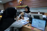 Petugas menyerahkan Surat Keterangan Catatan Kepolisian (SKCK) yang telah diterbitkan kepada pemohon di Sentra Pelayanan Kepolisian Terpadu (SPKT) Polresta Pontianak, Kalimantan Barat, Jumat (19/9/2025). Berdasarkan data Sat Intelkam Polresta Pontianak, sejak 15 hingga 19 September 2025 tercatat sekitar 600 pemohon SKCK untuk keperluan verifikasi persyaratan administrasi pemberkasan Pegawai Pemerintah dengan Perjanjian Kerja (PPPK) paruh waktu serta pendaftaran prajurit TNI. ANTARA FOTO/Jessica Wuysang