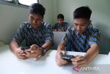 Tiga siswa mengakses materi pelajaran melalui aplikasi sekolah secara daring menggunakan gawai saat peluncuran program internet gratis untuk sekolah di SMAN 1 Pontianak, Kalimantan Barat, Selasa (23/9/2025). Pemerintah Provinsi Kalbar bersama PT Solusi Sinergi Digital Tbk dan Huawei Indonesia meluncurkan program internet gratis berkecepatan 100 Mbps melalui program CSR untuk satuan pendidikan se-Kalimantan Barat guna menghadirkan pemerataan literasi digital dan peningkatan kualitas pendidikan. ANTARA FOTO/Jessica Wuysang