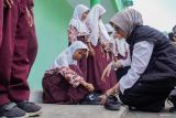Bupati Lumajang Indah Amperawati (kanan) membantu memakaikan sepatu gratis yang diterima siswa di MI Darul Muqomah, Lumajang, Jawa Timur, Rabu (24/9/2025). Pemkab Lumajang memberikan sepatu gratis kepada sejumlah siswa kurang mampu pada tiap kunjungan program Sehari Ngantor di Kecamatan Terpadu (Setor Madu) sebagai upaya bagian dari komitmen mewujudkan pendidikan yang inklusif dan merata bagi keluarga prasejahtera. ANTARA Jatim/Irfan Sumanjaya/mas.