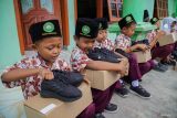 Siswa membawa sepatu gratis yang diterimanya di MI Darul Muqomah, Lumajang, Jawa Timur, Rabu (24/9/2025). Pemkab Lumajang memberikan sepatu gratis kepada sejumlah siswa kurang mampu pada tiap kunjungan program Sehari Ngantor di Kecamatan Terpadu (Setor Madu) sebagai upaya bagian dari komitmen mewujudkan pendidikan yang inklusif dan merata bagi keluarga prasejahtera. ANTARA Jatim/Irfan Sumanjaya/mas.