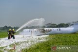 Petugas berusaha memadamkan api saat simulasi keadaan darurat di Bandara Husein Sastranegara, Bandung, Jawa Barat, Rabu (24/9/2025). PT Angkasa Pura II bersama Lanud Husein Sastranegara menggelar simulasi keadaan darurat yang ditujukan untuk menguji prosedur penanganan keadaan darurat sekaligus memperkuat koordinasi antara pihak bandara, TNI AU, Basarnas, aparat keamanan, tenaga medis, dan instansi terkait lainnya. ANTARA FOTO/Raisan Al Farisi/agr