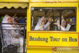 Pengantin melambaikan tangan saat menaiki bus Bandros seusai akad nikah secara gratis di depan Mal Pelayanan Publik Kota Bandung, Bandung, Jawa Barat, Jumat (26/9/2025). Pemerintah Kota Bandung menggelar nikah gratis bagi 10 pasangan dengan sekaligus menyediakan buku nikah, rias pengantin, mahar hingga kartu keluarga secara langsung sebagai bentuk pelayanan terpadu bagi masyarakat. ANTARA FOTO/Novrian Arbi/agr