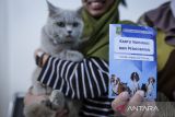 Warga menunjukkan kartu vaksinasi kucing peliharaannya usai disuntikkan vaksin rabies di UPTD Pusat Kesehatan Hewan Kota Tangerang, Banten, Jumat (26/9/2025). Dinas Ketahanan Pangan Kota Tangerang menyediakan 50 vaksin rabies gratis untuk hewan kucing, anjing, kera dan musang dalam rangka Hari Rabies Sedunia guna mengurangi risiko penularannya kepada manusia. ANTARA FOTO/Putra M. Akbar/gp
