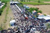 Foto udara warga melihat parade kereta penumpang dengan 11 Livery di Stasiun Tulangan, Sidoarjo, Jawa Timur, Minggu (28/9/2025). Museum Rekor-Dunia Indonesia (MURI) mencatat dua penghargaan berupa parade kereta penumpang dengan 11 Livery terbanyak dari masa ke masa dan fashion show pakaian adat nusantara pertama di atas kereta yang sedang melaju. Antara Jatim/Umarul Faruq