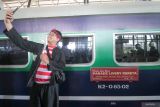 Penumpang berfoto dengan latar belakang gerbong kereta saat parade kereta penumpang dengan 11 Livery di Stasiun Tulangan, Sidoarjo, Jawa Timur, Minggu (28/9/2025). Museum Rekor-Dunia Indonesia (MURI) mencatat dua penghargaan berupa parade kereta penumpang dengan 11 Livery terbanyak dari masa ke masa dan fashion show pakaian adat nusantara pertama di atas kereta yang sedang melaju. Antara Jatim/Umarul Faruq