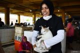 Dokter hewan menggendong kucing untuk disuntik vaksin rabies di kawasan Pasar Besar Kota Madiun, Jawa Timur, Senin (29/9/2025). Dinas Ketahanan Pangan dan Pertanian Kota Madiun melakukan vaksinasi rabies pada kucing jalanan di delapan lokasi sebagai pencegahan penyakit rabies guna terciptanya keamanan dan kenyamanan lingkungan dalam rangka memperingati Hari Rabies Sedunia. ANTARA Jatim/Siswowidodo/mas.