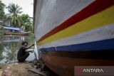Pekerja mengecat badan perahu nelayan di Desa Karang Serang, Kabupaten Tangerang, Banten, Selasa (30/9/2025). Menurut pekerja jasa perbaikan perahu berupa pengecatan, penambalan hingga penggantian kayu  tersebut berkisar Rp15 juta - Rp30 juta per unitnya tergantung jenis kerusakan dan ukuran perahu. ANTARA FOTO/Putra M. Akbar/gp