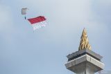 Seorang prajurit TNI terjun payung membawa Bendera Merah-putih saat Upacara Peringatan HUT ke-80 TNI di kawasan Silang Monas, Jakarta, Minggu (5/10/2025). Peringatan HUT ke-80 TNI tersebut mengangkat tema besar TNI Prima , TNI Rakyat, Indonesia Maju. ANTARA FOTO/Asprilla Dwi Adha/wsj.