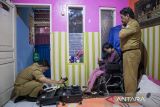 Petugas memotret warga penyandang disabilitas untuk proses perekaman data KTP elektronik saat layanan jemput bola di rumahnya di Cigugur, Kota Cimahi, Jawa Barat, Selasa (7/10/2025). Pelayanan perekaman data KTP elektronik yang dilakukan Dinas Kependudukan dan Pencatatan Sipil (Disdukcapil) Kota Cimahi dengan cara jemput bola tersebut untuk mempercepat serta mempermudah warga lansia dan penyandang disabilitas terdaftar dalam administrasi kependudukan sebagai syarat untuk mendapatkan layanan publik hingga program pemerintah. ANTARA FOTO/Abdan Syakura/agr