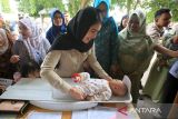 Wakil Menteri Kependudukan dan Pembangunan Keluarga/Wakil Kepala  BKKBN, Ratu Ayu Isyana Bagoes Oka (kedua kiri) menggendong bayi untuk penimbangan saat kunjungan ke Posyandu desa Ie Masen, Banda Aceh, Aceh,  Kamis (9/10/2025). Kunjungan Ratu Ayu Isyana Bagoes Oka ke daerah itu,  selain meninjau dapur SPPG juga melihat langsung pelayanan Posyandu dan pemberian makan bergizi untuk ibu hamil, vakasinasi anak  serta pemeriksaan kesehatan gratis.  ANTARA FOTO/Ampelsa.