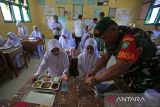 Anggota Babinsa membantu membuka nampan berisi menu  Makanan Bergizi Gratis (MBG) untuk siswa  saat launching perdana di  Sekolah Madrasyah Ibtidaiyah Negeri (MIN) 18 desa Biluy, kecamatan Darul Kamal, kabupaten Aceh Besar, Aceh, Senin (13/10/2025). Badan Gizi Nasional berupaya memperluas jangkuan program Makan Bergizi Gratis (MBG) hingga ke wilayah pedalaman di Aceh dengan melakukan launching serentak MBG di lima sekolah berbeda jenjang pendidikan  dengan total penerima sebanyak 1.192 siswa. ANTARA FOTO/Ampelsa.