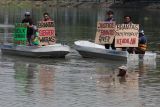 Sejumlah aktivis lingkungan dari Ecoton membentangkan poster di atas perahu saat aksi Besuk Sungai Brantas di Surabaya, Jawa Timur, Selasa (14/10/2025). Aksi itu menyerukan sejumlah aspirasi di antaranya mengajak masyarakat menjaga kualitas air sungai Brantas dengan tidak membuang sampah ke sungai, mewajibkanÂ  perusahaan industri mengolah limbah terlebih dahulu sampai memenuhi baku mutu sebelum dibuang ke sungai dan mengimbau pemerintah setempat membentuk badan khusus pengelola sungai Brantas yang mengawasi kualitas dan kelestarian ekosistem sungai Brantas. ANTARA Jatim/Didik Suhartono/mas.