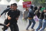 Pengunjuk rasa berlindung dari siraman air water canon  saat Simulasi Sistem Pengamanan Kota (Sispamkota) di parkir timur Gelora Delta Sidoarjo, Jawa Timur, Rabu (15/10/2025). Kegiatan yang melibatkan ratusan personel gabungan TNI dan Polri itu guna meningkatkan kemampuan personel dan langkah pengendalian massa maupun pemulihan situasi ketika terjadi unjuk rasa yang berpotensi mengakibatkan kerusuhan. Antara Jatim/Umarul Faruq