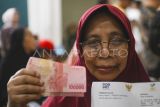 Penerima BLT menunjukan uang tunai yang diterima saat pengumuman paket stimulus ekonomi di Kantor Pos Cikini, Jakarta, Jumat (17/10/2025). Pemerintah mengumumkan paket stimulus tambahan berupa BLT tambahan senilai total Rp30 triliun dan perluasan program magang berbayar menjadi 80 ribu peserta. ANTARA FOTO/Hafidz Mubarak A/YU