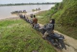 Pengendara sepeda motor dan warga mengantre untuk menyeberangi Sungai Batanghari dari Desa Keranggan menuju Desa Berembang di Sekernan, Muaro Jambi, Jambi, Senin (20/10/2025). Warga setempat menyebutkan, sedikitnya 200 warga Sekernan yang berada di tepi Daerah Aliran Sungai (DAS) Batanghari masih menggunakan perahu untuk menyeberangi sungai terpanjang di Sumatera itu setiap harinya dengan tarif umum Rp7 ribu per motor pulang-pergi (PP) dan Rp5 ribu per motor PP untuk pelajar karena tidak adanya jembatan penghubung. ANTARA FOTO/Wahdi Septiawan/YU