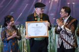 Menteri Kebudayaan Fadli Zon (kanan) didampingi Dirjen Diplomasi, Promosi dan Kerja Sama Kebudayaan Endah T.D. Retno Astuti (kiri) memberikan penghargaan kepada perwakilan pemenang kategori lembaga dan perorangan asing sejarawan Ulrich Kozok (tengah) saat Malam Apresiasi Anugerah Kebudayaan Indonesia 2025 di Kementerian Kebudayaan, Senayan, Jakarta, Selasa (21/10/2025). Kementerian Kebudayaan memberikan 12 kategori penghargaan sebagai bentuk apresiasi kepada individu, komunitas, dan lembaga yang telah berdedikasi dan berkontribusi dalam menjaga serta memajukan kebudayaan Indonesia. ANTARA FOTO/Sulthony Hasanuddin/YU