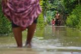 Warga melintasi banjir di Desa Sidorejo, Kecamatan Rowokangkung, Lumajang, Jawa Timur, Sabtu (25/10/2025). Sedikitnya 400 kepala keluarga terdampak banjir setinggi 50-90 sentimeter akibat luapan Sungai Banter setelah hujan deras mengguyur wilayah setempat. ANTARA Jatim/Irfan Sumanjaya/mas.