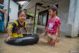Anak-anak bermain saat banjir di Desa Sidorejo, Kecamatan Rowokangkung, Lumajang, Jawa Timur, Sabtu (25/10/2025). Sedikitnya 400 kepala keluarga terdampak banjir setinggi 50-90 sentimeter akibat luapan Sungai Banter setelah hujan deras mengguyur wilayah setempat. ANTARA Jatim/Irfan Sumanjaya/mas.