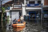 Satpam BRI menjemput nasabah bank menggunakan perahu karet saat banjir di Jalan Kaligawe Raya, Semarang, Jawa Tengah, Rabu (29/10/2025). Menurut data sementara BPBD Kota Semarang sebanyak 39.405 jiwa dari 29.772 KK di 18 wilayah terdampak banjir yang melanda Kota Semarang akibat dari anomali cuaca dengan intensitas hujan tinggi sejak Selasa (21/10). ANTARA FOTO/Aprillio Akbar/nz
