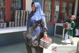 Guru bersama siswa membawa  nampan berisi menu Makanan Bergizi Gratis (MBG)  di Sekolah Dasar Negeri 20 Banda Aceh, Aceh, Kamis (30/10/2025). Badan Gizi Nasional (BGN) menegaskan batasan kapasitas porsi makanan harian  yang disiapkan setiap Satuan Pelayanan Pemenuhan Gizi  (SPPG)  dalam program Makanan Bergizi Gratis (MBG) maksimal sebanyak 3.000 porsi per hari dengan syarat SPPG memiliki tenaga juru masak yang kompeten dan bersertifikat dariBNSP. ANTARA FOTO/Ampelsa.