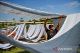 Pekerja mengeringkan kain untuk dijadikan kain pel di Desa Laksana, Kecamatan Ibun, Kabupaten Bandung, Jawa Barat, Kamis (30/10/2025). Pekerja menyebutkan pada musim penghujan, produksi kain pel yang dijual dengan harga Rp50.000 per kodi tersebut mengalami penurunan hingga 50 persen atau hanya mampu memproduksi 150 kodi per minggu dibandingkan dengan musim kemarau yang mampu menembus hingga 300 kodi per minggu. ANTARA FOTO/Raisan Al Farisi/agr