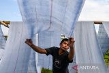 Pekerja mengeringkan kain untuk dijadikan kain pel yang telah selesai di produksi di Desa Laksana, Kecamatan Ibun, Kabupaten Bandung, Jawa Barat, Kamis (30/10/2025). Pekerja menyebutkan pada musim penghujan, produksi kain pel yang dijual dengan harga Rp50.000 per kodi tersebut mengalami penurunan hingga 50 persen atau hanya mampu memproduksi 150 kodi per minggu dibandingkan dengan musim kemarau yang mampu menembus hingga 300 kodi per minggu. ANTARA FOTO/Raisan Al Farisi/agr
