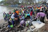 Sejumlah pelajar memungut sampah dari pantai di kawasan Jembatan Suramadu, Surabaya, Jawa Timur, Sabtu (1/11/2025). Sekitar 210 pelajar tingkat Sekolah Dasar dan Sekolah Menengah Pertama, keluarga dari pelajar, Komunitas Tunas Hijau dan petugas Dinas Lingkungan Hidup Kota Surabaya bergotong royong membersihkan pantai itu dari sampah agar pantai yang menjadi salah satu destinasi wisata tersebut terjaga kebersihannya. ANTARA Jatim/Didik Suhartono/mas.