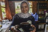 Pekerja menyuguhkan secangkir teh Kayu Aro yang telah melewati proses uji di salahsatu kafe di Kerinci, Jambi.