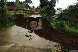 Sebuah mobil berhenti di salah satu ujung jalan yang amblas terseret longsor di Desa Nyawangan, Tulungagung, Jawa Timur, Senin (3/11/2025). Jalan antardesa di lereng Gunung Wilis itu amblas terseret longsor di kedalaman 20 meter menyebabkan akses terganggu. Antara Jatim/Destyan Sujarwoko/um
