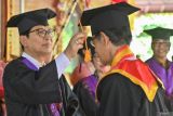 Bupati Badung I Wayan Adi Arnawa (kiri) memindahkan tali toga seorang peserta didik lansia angkatan pertama Sekolah Lansia Werdha Winangun Urip yang mengikuti wisuda di Kabupaten Badung, Bali, Senin (10/11/2025). Wisuda tersebut dilakukan setelah para lansia selesai mengikuti berbagai kegiatan pendidikan dan pelatihan di sekolah tersebut seperti pada aspek kesehatan keluarga, keterampilan diri hingga pengembangan sosial. ANTARA FOTO/Fikri Yusuf/wsj.