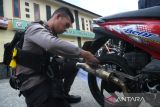Petugas kepolisian memegang knalpot brong dari motor milik  yang diamankan di Polresta Pontianak, Kalimantan Barat, Selasa (11/11/2025). Polresta Pontianak mengamankan 49 kendaraan bermotor dalam patroli pada Sabtu (8/11) malam karena terlibat balap liar, menggunakan knalpot brong bersuara bising, dan tidak memiliki dokumen resmi, sebagai bagian dari operasi cipta kondisi menjaga ketertiban di Kota Pontianak. ANTARA FOTO/Jessica Wuysang