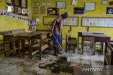 Penjaga sekolah membersihkan sisa banjir di dalam kelas di SD Negeri Pamarican 2, Kota Serang, Banten, Kamis (13/11/2025). Sebanyak dua sekolah dasar di daerah tersebut terdampak banjir sejak Senin (10/11) akibat posisi sekolah yang lebih rendah dari jalan disertai buruknya saluran drainase sehingga mengakibatkan kegiatan belajar mengajar terpaksa dilaksanakan secara daring. ANTARA FOTO/Muhammad Bagus Khoirunas/gp