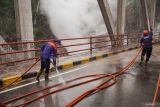Petugas menyemprotkan air untuk membersihkan material vulkanik Gunung Semeru di Jembatan Besuk Kobokan, Kecamatan Candipuro, Lumajang, Jawa Timur, Sabtu (22/11/2025). Pemerintah Kabupaten Lumajang menyiagakan tim gabungan untuk memberikan keamanan untuk pengendara yang melintas di kawasan tersebut menyusul risiko hujan abu dan potensi letusan sekunder dari aktivitas Erupsi Semeru. Antara Jatim/Irfan Sumanjaya/um