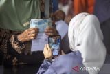 Petugas memotret warga penerima Bantuan Langsung Tunai Sementara Kesejahteraan Rakyat (BLTS Kesra) di Kantor Pos, Indramayu, Jawa Barat, Senin (24/11/2025). Sebanyak 91.557 Keluarga Penerima Manfaat (KPM) di Indramayu menerima BLTS Kesra sebesar Rp900.000 untuk periode Oktober hingga Desember. ANTARA FOTO/Dedhez Anggara/agr