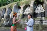 Perempuan Bali berbincang dengan wisatawan mancanegara di area situs arkeologi kuno saat acara cerita di balik sejarah di Daya Tarik Wisata (DTW) Gunung Kawi, Gianyar, Bali, Selasa (25/11/2025). Kegiatan yang digelar Balai Pelestarian Kebudayaan Wilayah XV tersebut untuk mengenali peninggalan kebudayaan dan sejarah Bali yakni situs arkeologi kuno berupa kompleks candi yang dipahat di dinding tebing. ANTARA FOTO/Nyoman Hendra Wibowo/wsj.