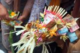 Seorang warga menyiapkan sarana upacara yang berisi uang saat tradisi Mesuryak pada perayaan Hari Raya Kuningan di Desa Bongan Gede, Tabanan, Bali, Sabtu (29/11/2025). Tradisi berebut uang yang digelar setiap Hari Raya Kuningan tersebut bertujuan mengantarkan roh para leluhur kembali ke surga dengan rasa suka cita serta bermakna sebagai rasa syukur sekaligus mempererat kebersamaan keluarga dan masyarakat. ANTARA FOTO/Nyoman Hendra Wibowo/wsj.