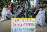 Kapster mencukur rambut warga saat aksi sosial pangkas rambut bayar seikhlasnya di Alun-alun Ahmad Yani, Kota Tangerang, Banten, Minggu (30/11/2025). Aksi yang dilakukan oleh 15 kapster alumni Balai Latihan Kerja Kota Tangerang tersebut untuk mengumpulkan dana bantuan yang hasilnya akan disumbangkan bagi korban bencana alam di Aceh, Sumatera Utara dan Sumatera Barat. ANTARA FOTO/Putra M. Akbar/gp
