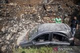 Warga melihat kondisi mobil yang rusak akibat tertimpa material longsor di Desa Sariwangi, Parongpong, Kabupaten Bandung Barat, Jawa Barat, Senin (1/12/2025). Berdasarkan data BPBD Kabupaten Bandung Barat, sebanyak satu unit mobil rusak berat dan tiga orang luka-luka akibat longsor dinding penahan tanah dari proyek gudang di kawasan itu pada Minggu (30/11) malam. ANTARA FOTO/Abdan Syakura/agr