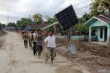 Warga bergotong royong memikul lampu jalan tenaga surya untuk peneranggan darurat pascabanjir bandang di Desa Aek Garoga, Kecamatan Batang Toru, Kabupaten Tapanuli Selatan, Sumatera Utara,  Kamis (4/12/2025).  Warga menyelamatkan lampu jalan tenaga surya yang tertimbun tanah akibat banjir bandang untuk difungsikan lagi sebagai penerangan darurat di rumah mereka yang listik masih mati.ANTARA/Yudi