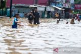 Warga berjalan melintasi banjir di Jalan Raya Dayeuhkolot, Kabupaten Bandung, Jawa Barat, Jumat (5/12/2025). Badan Penanggulangan Bencana Daerah (BPBD) Kabupaten Bandung menyatakan sedikitnya 34 ribu jiwa dari tiga kecamatan di Kabupaten Bandung terdampak banjir setinggi 10cm hingga 150cm akibat hujan dengan intensitas tinggi serta luapan Sungai Citarum. ANTARA FOTO/Novrian Arbi/agr