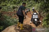 Pengendara melintas di dekat bagian jalan yang amblas pascalongsor di Desa Nanggerang, Cililin, Kabupaten Bandung Barat, Jawa Barat, Jumat (5/12/2025). Bencana tanah longsor yang terjadi pada Kamis (4/12) tersebut menyebabkan jalan yang menghubungkan Desa Nanggerang dengan Desa Mukapayung amblas dan tertutup material longsor sehingga hanya bisa dilalui oleh kendaraan roda dua secara bergantian. ANTARA FOTO/Abdan Syakura/agr
