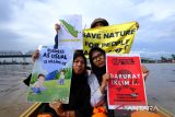 Sejumlah relawan dari organisasi peduli lingkungan membentangkan poster berisi seruan penyelamatan lingkungan saat mengikuti aksi di kawasan Sungai Kapuas, Pontianak, Kalimantan Barat, Rabu (3/12/2025). Dalam aksi yang digelar para relawan dari Greenpeace, Tim Cegah Api, Gemawan, GMNI Kalbar, dan Extinction Rebellion Pontianak untuk memperingati Hari Relawan Sedunia tersebut mereka menyuarakan sejumlah isu, antara lain selamatkan bumi, penghentian pembakaran hutan dan lahan, pukul mundur krisis iklim, serta penyelamatan hutan dan ekosistem gambut. ANTARA FOTO/Jessica Wuysang 