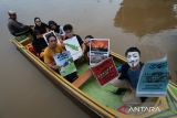 Sejumlah relawan dari organisasi peduli lingkungan membentangkan poster berisi seruan penyelamatan lingkungan saat mengikuti aksi di kawasan Sungai Kapuas, Pontianak, Kalimantan Barat, Rabu (3/12/2025). Dalam aksi yang digelar para relawan dari Greenpeace, Tim Cegah Api, Gemawan, GMNI Kalbar, dan Extinction Rebellion Pontianak untuk memperingati Hari Relawan Sedunia tersebut mereka menyuarakan sejumlah isu, antara lain selamatkan bumi, penghentian pembakaran hutan dan lahan, pukul mundur krisis iklim, serta penyelamatan hutan dan ekosistem gambut. ANTARA FOTO/Jessica Wuysang